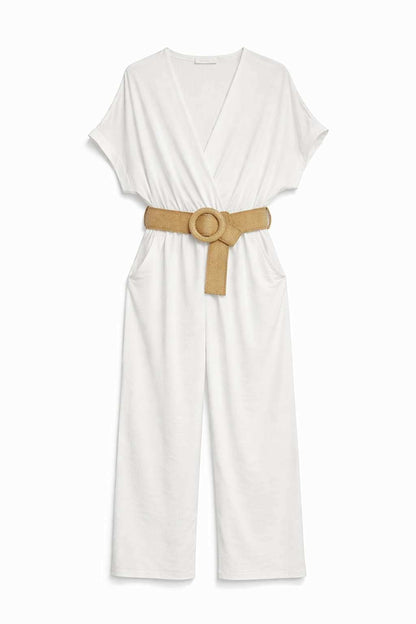 Combinaison pantalon blanche col V croisé portefeuille, manches courtes amples, ceinture tressée boucle ronde dorée et deux poches latérales, présentée à plat sur fond blanc