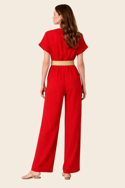 Dos d'une femme en combinaison pantalon rouge col V croisé, ceinture tressée dorée nouée à la taille, jambes palazzo fluides