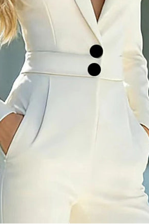 Combinaison blazer blanche gros plan sur la fermeture à boutons noirs et la finition de la ceinture intégrée.