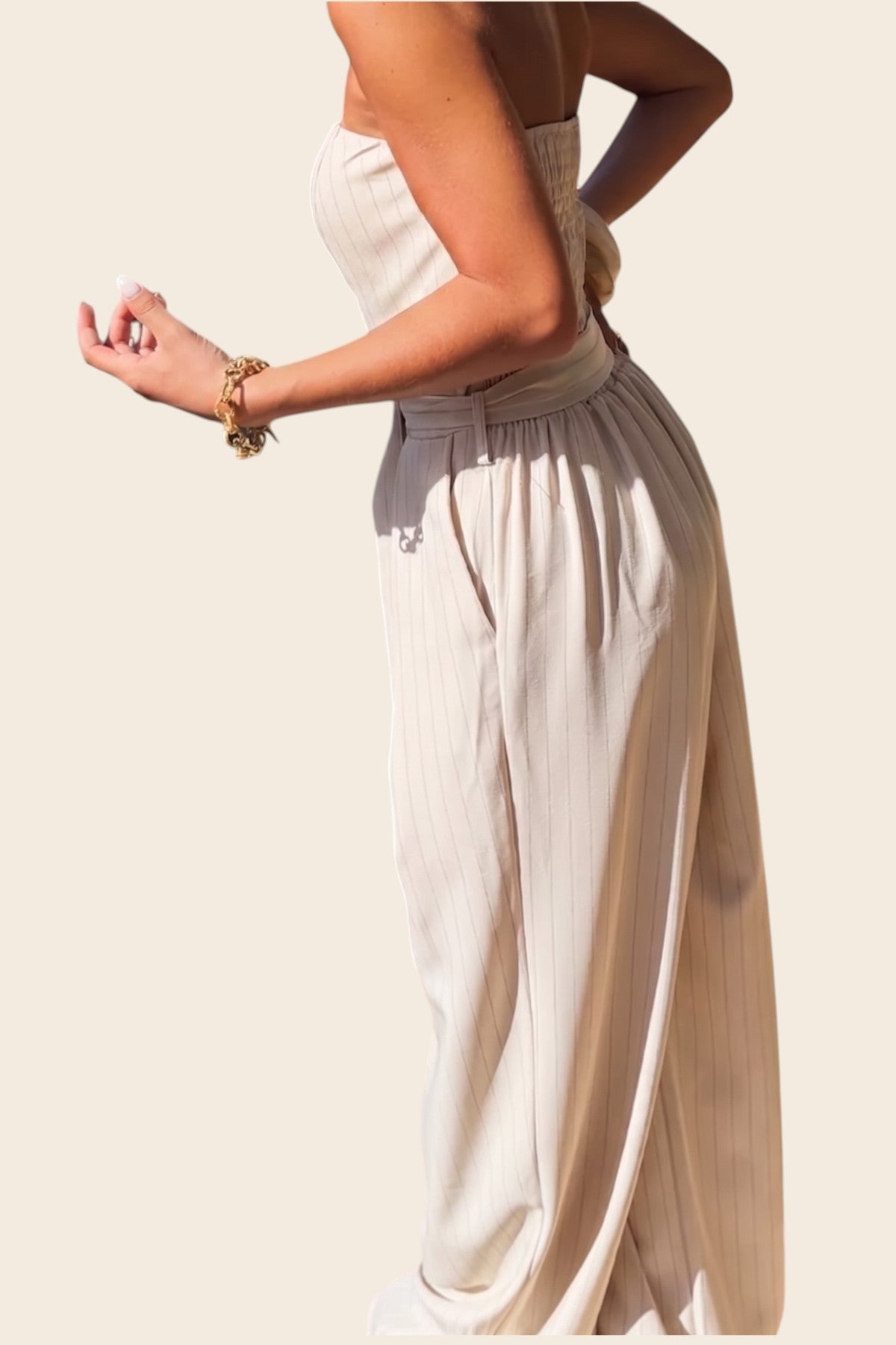 femme vue de profilequi porte une combinaison bustier beige a rayure 