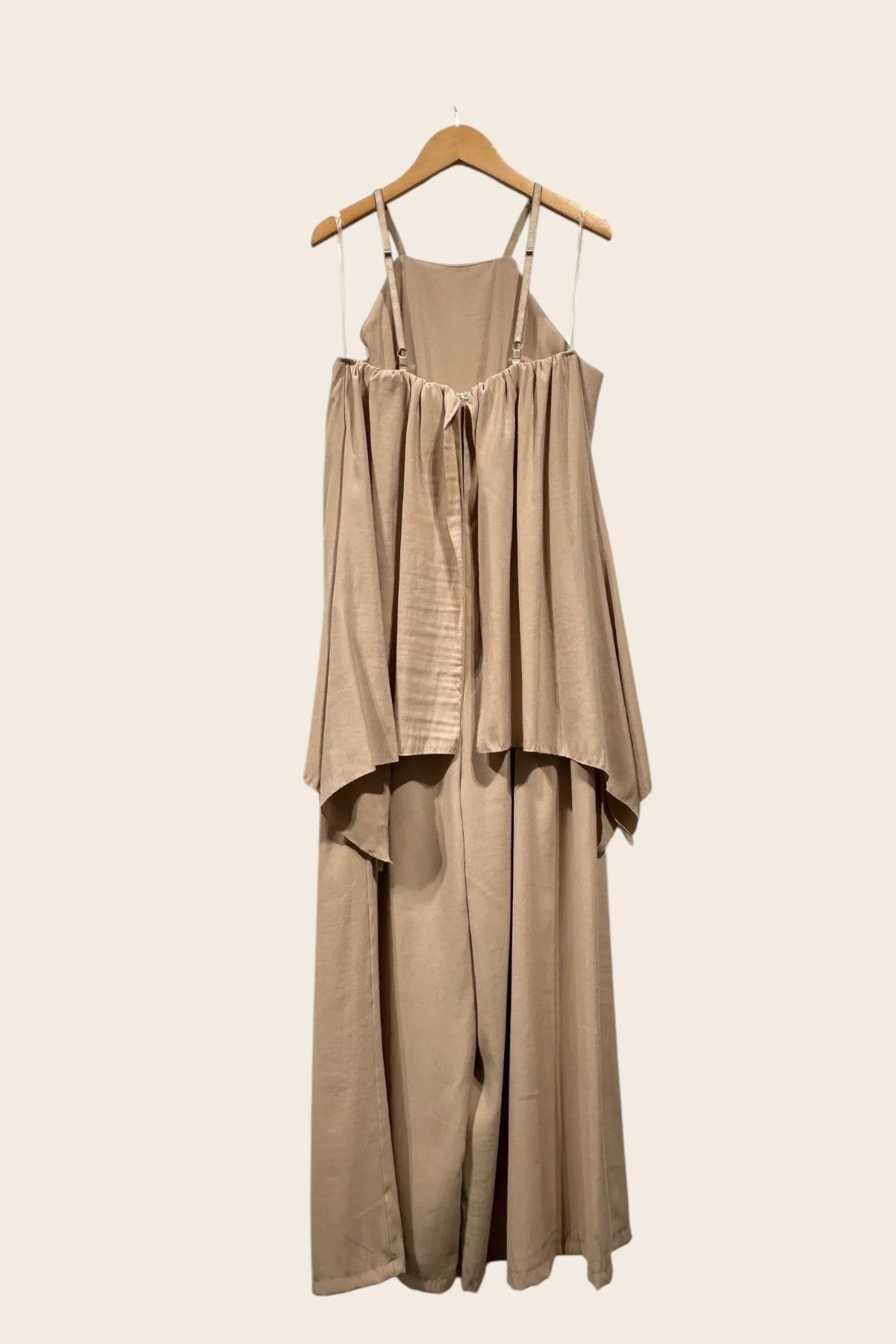 Combinaison fluide beige vue de dos sur cintre, bretelles fines ajustables réglables, dos froncé et buste évasé effet cape retombant sur un pantalon large palazzo