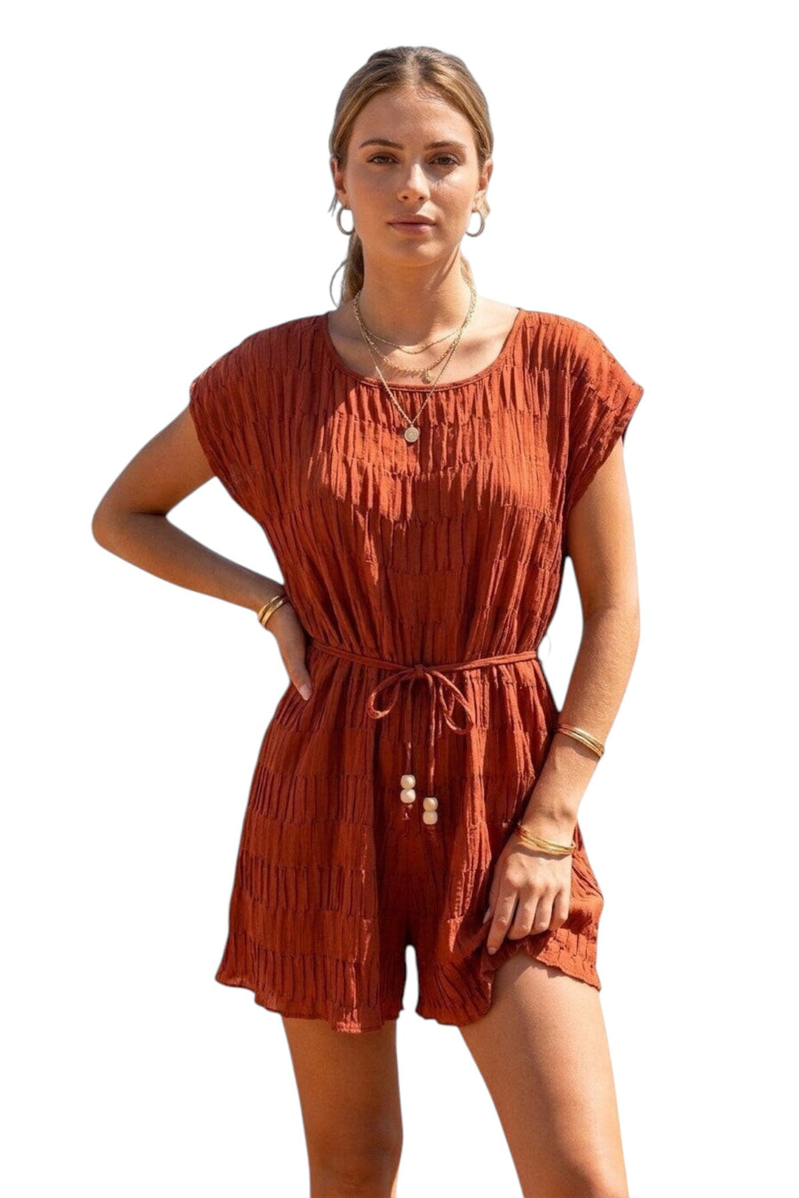 Femme portant un combishort terracotta effet plissé texturé, col rond, manches courtes tombantes et cordon à nouer avec perles à la taille, short évasé, vue de face sur fond blanc