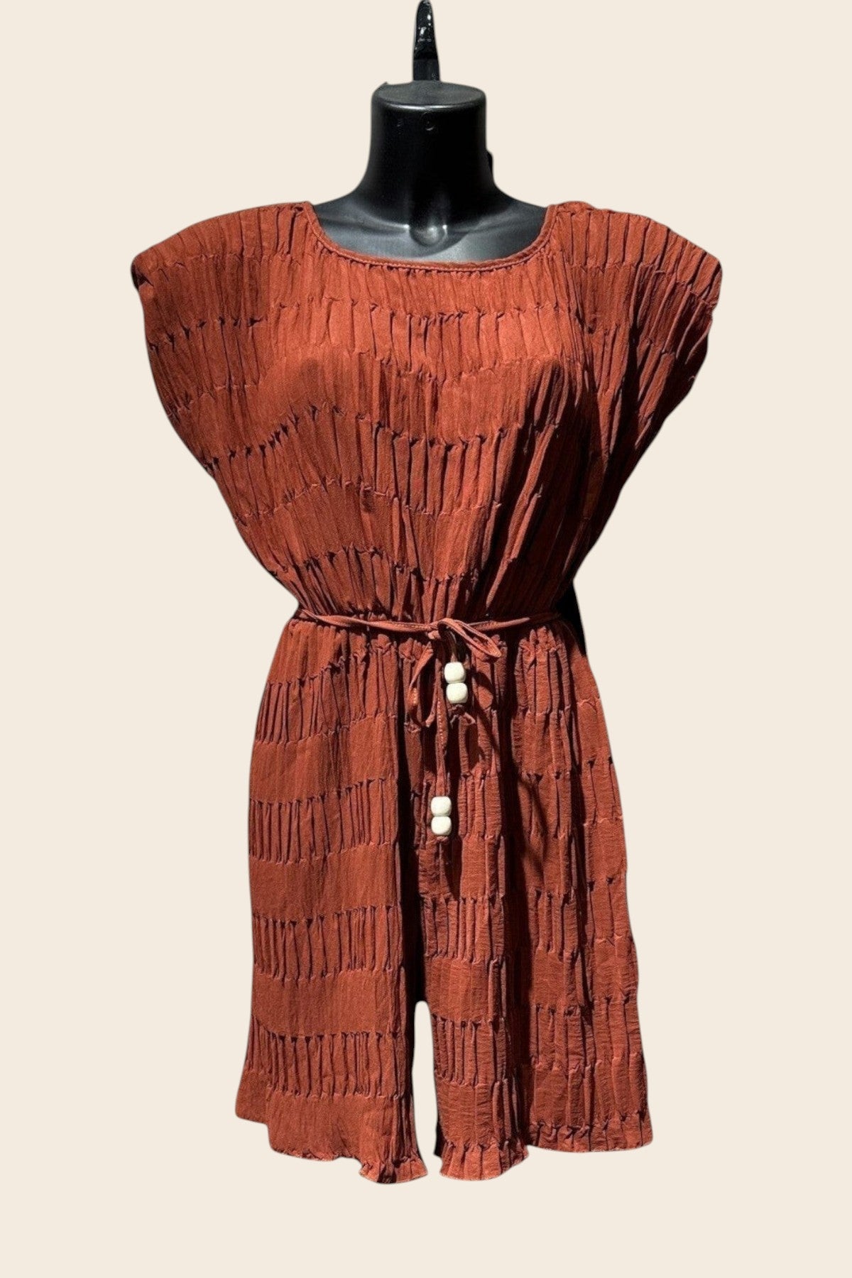 Combishort terracotta effet plissé texturé présenté sur mannequin, col rond, manches courtes tombantes, cordon à nouer avec perles à la taille, short évasé finition volant