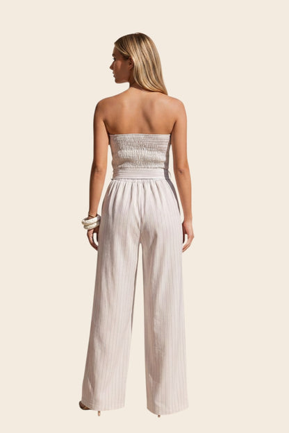 Vue arrière d'une femme portant la combinaison bustier beige maison de la combi avec dos smoccé et jambes larges