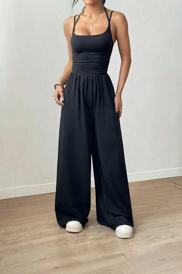 Combinaison noire dos nu chic La Esmeralda, bretelles spaghetti, taille smockée, pantalon large. Polyester et élasthanne.