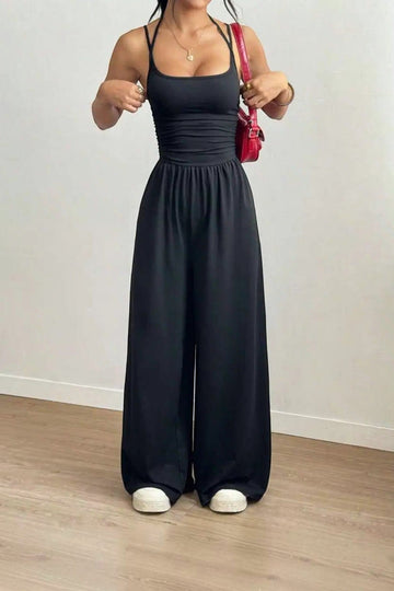Combinaison noire dos nu chic La Esmeralda, bretelles fines, taille smockée, jambes larges, en polyester et élasthanne.