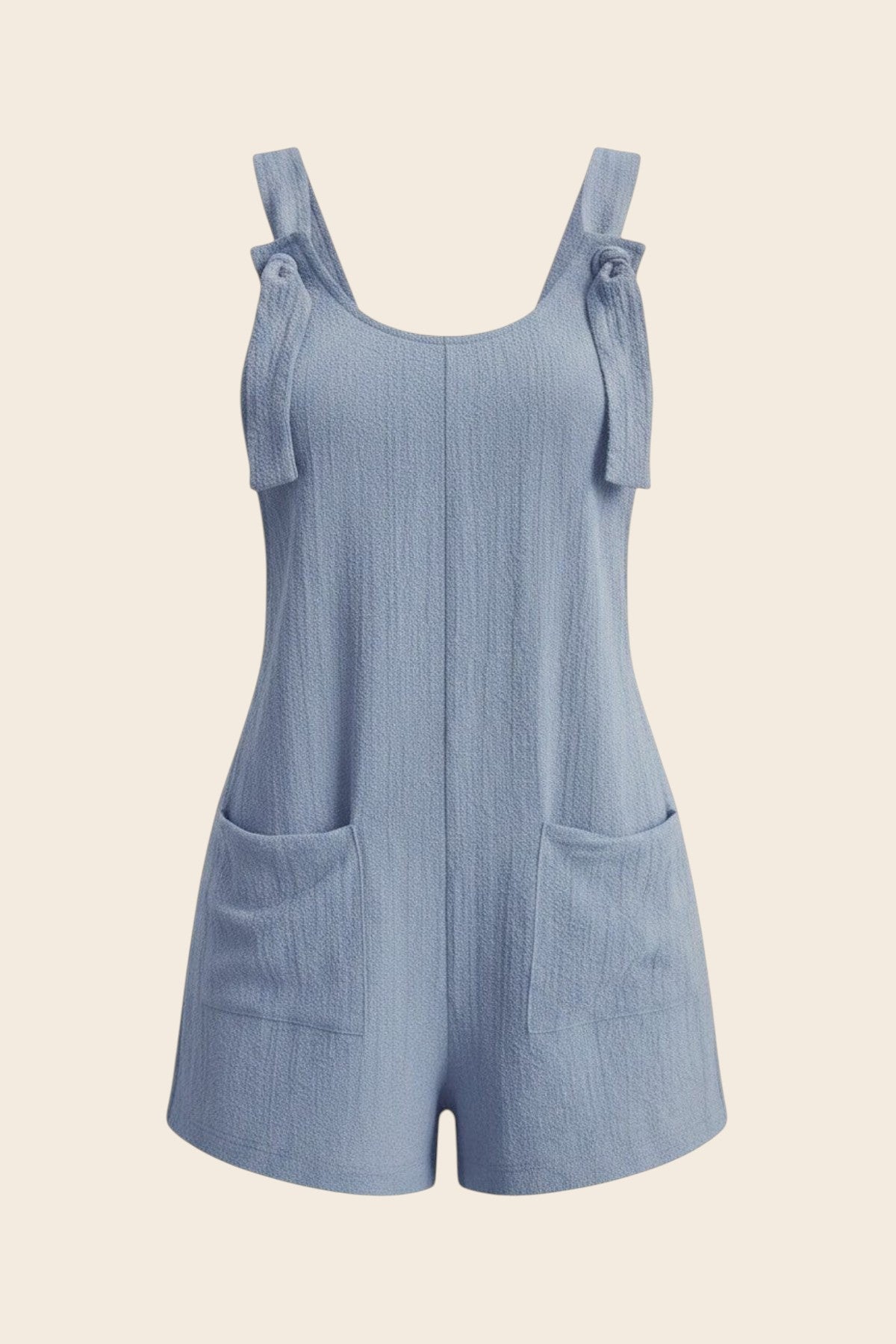 Combinaison short bleu ciel en polyester et élasthanne, avec liens à nouer sur les épaules et poches plaquées. Maison de la Combi.