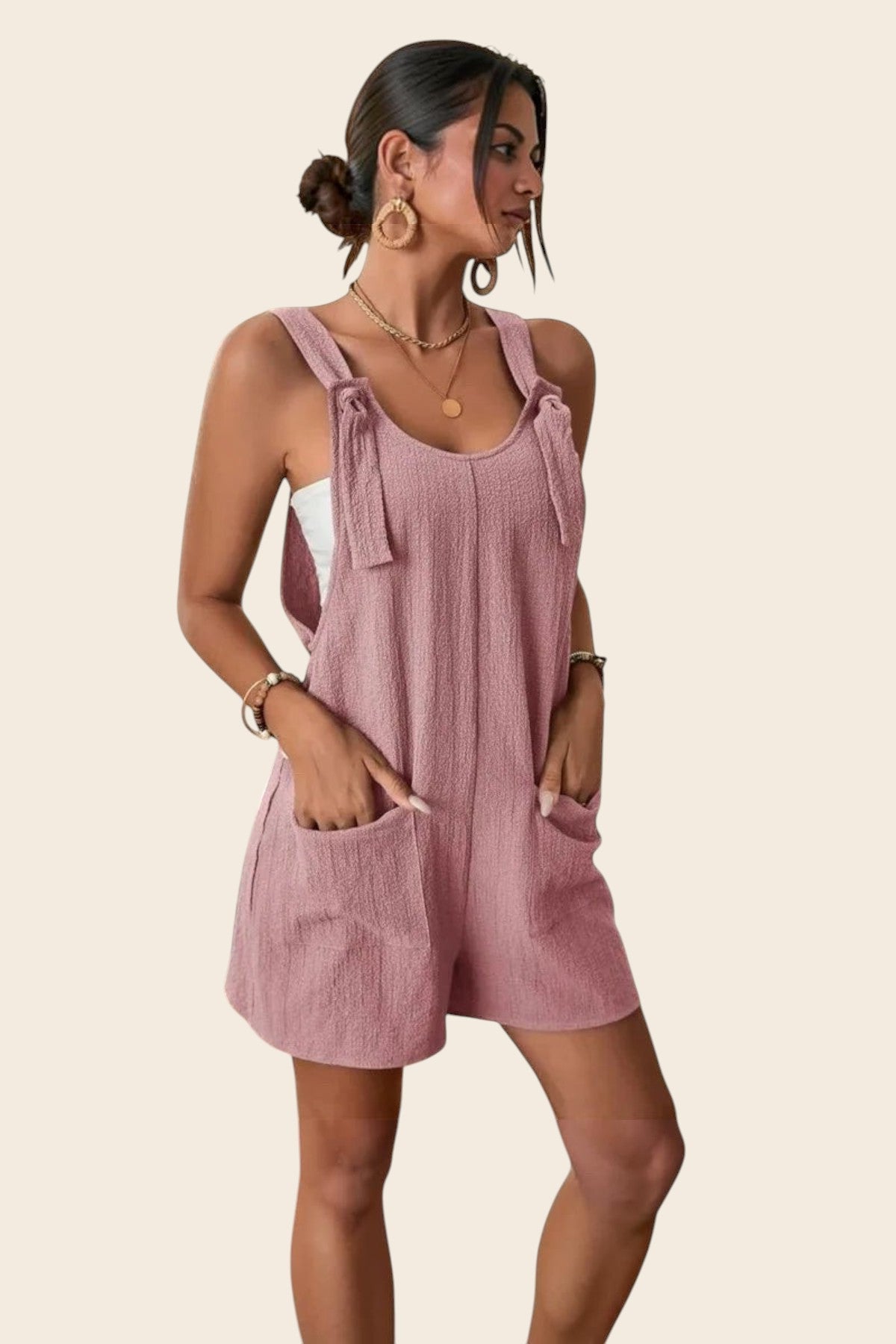 Combinaison short rose poudré en polyester et élasthanne, avec détails à nouer sur les épaules et poches plaquées.