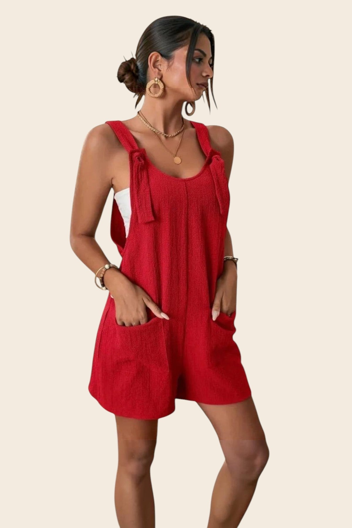Combinaison short rouge en polyester et élasthanne, avec détails à nouer sur les bretelles et poches plaquées. Maison de la Combi.